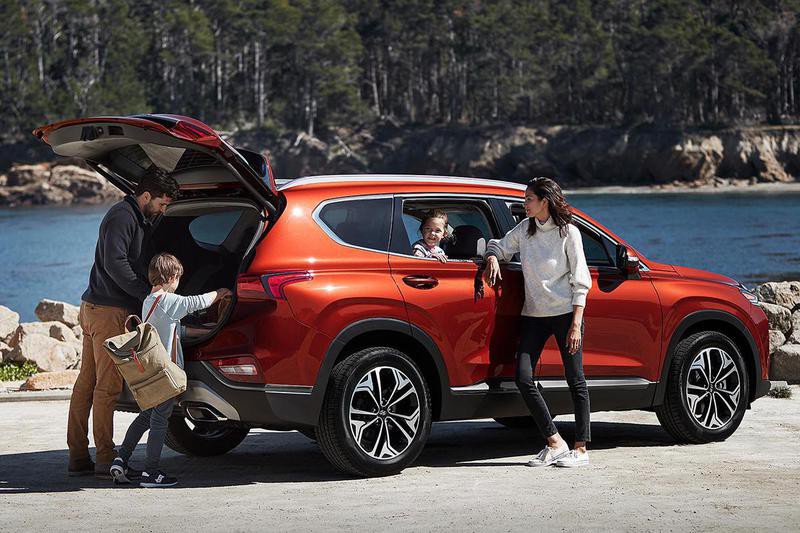 young family with two children in red car