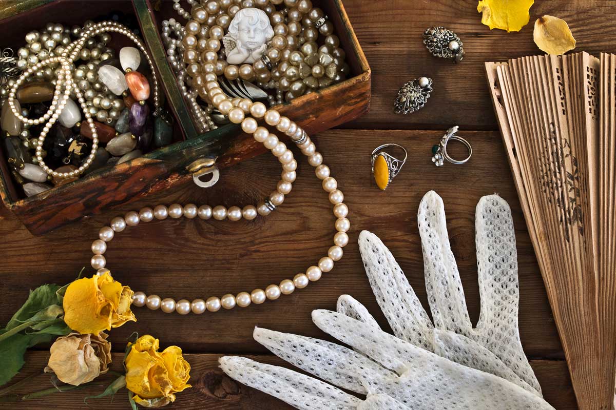 items scattered on wooden surface - pearls, rings, gloves and flower