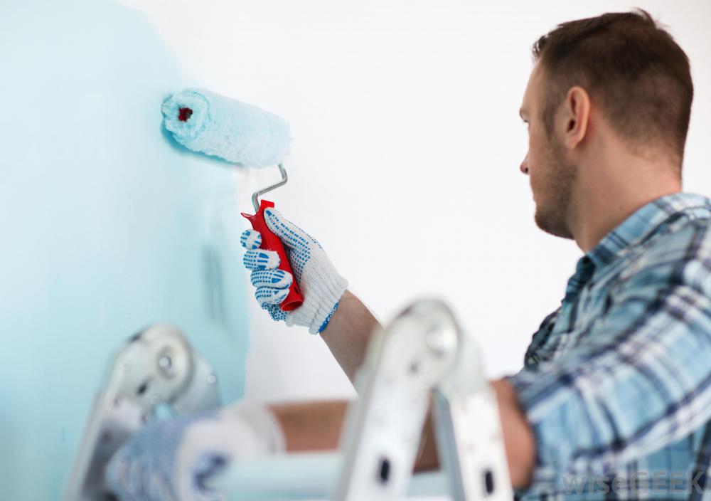 man on ladder painting wall