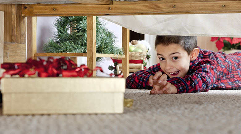 little boy laying on ground looking for christmas presents