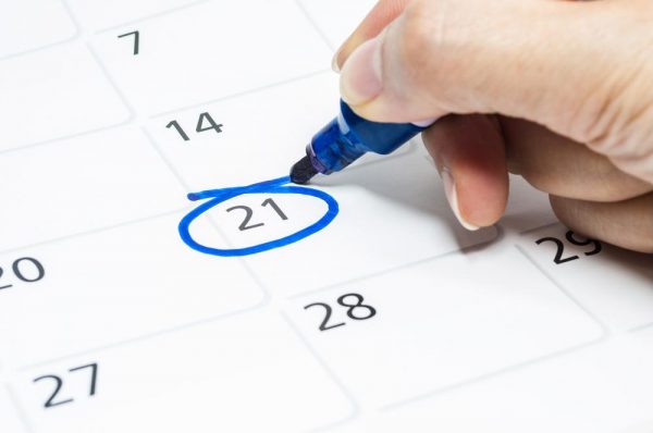 a person circling a date on the calendar with a blue marker