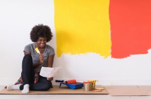 a black afro woman choosing which paint to color her walls