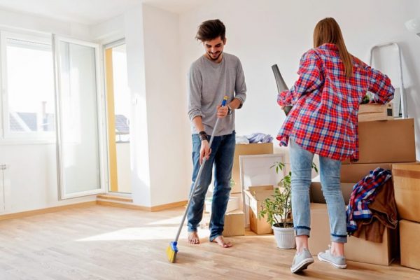 a young couple spring cleaning while the man is sweeping the floor