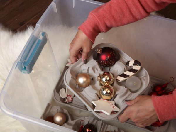 A woman organising christmas ornaments in a plastic box