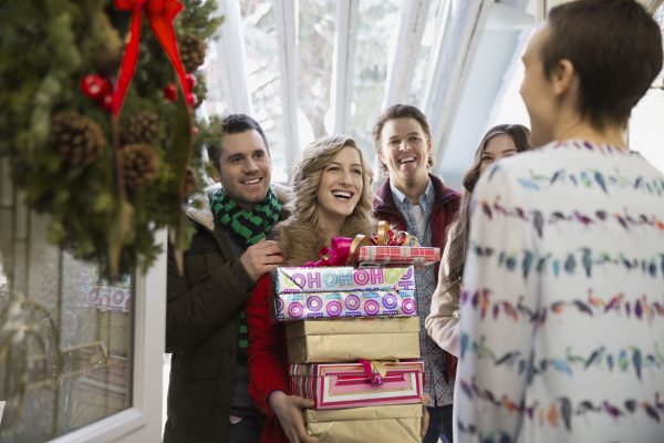 A woman holding a stack of gifts while being surrounded by her friends