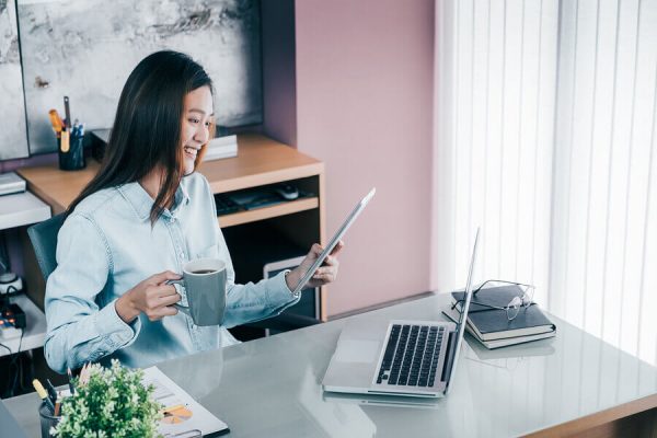 A happy asian woman reading on her digital tablet