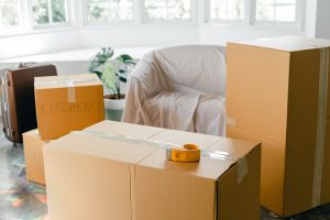 4 cardboard storage boxes with sicky tape in a room and a suitcase