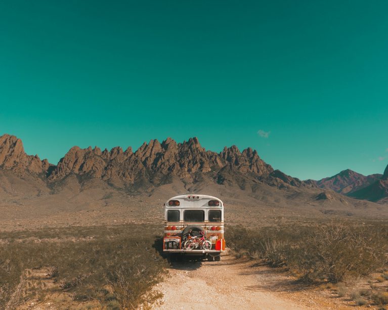 white and red bus off-road near the mountains